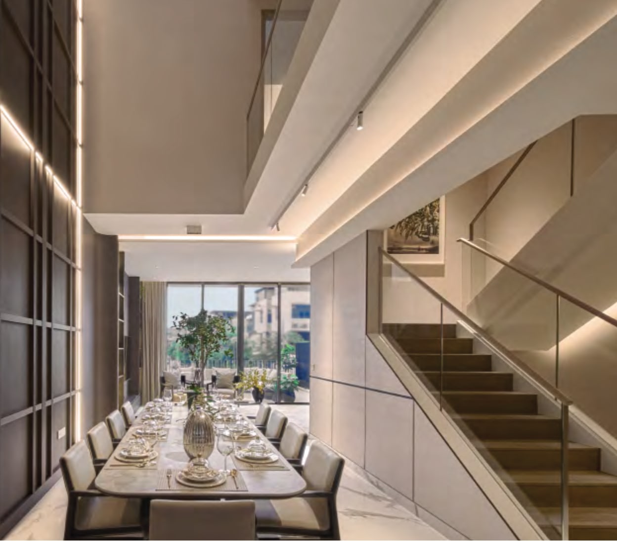 Interior picture of a long dining table beside a staircase under a tall ceiling