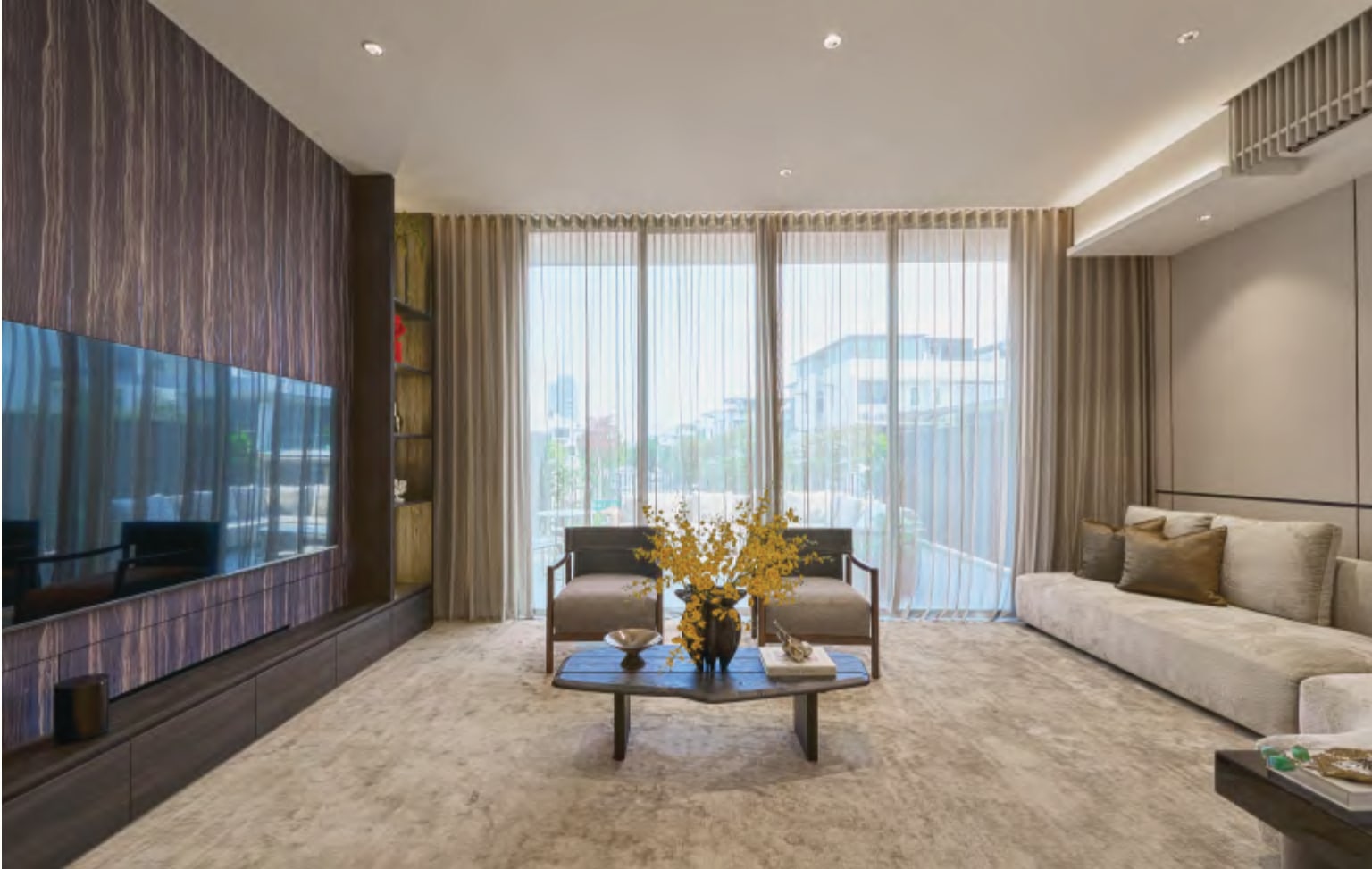 Interior picture of a living room with a long television wall and tall windows with sheer curtains