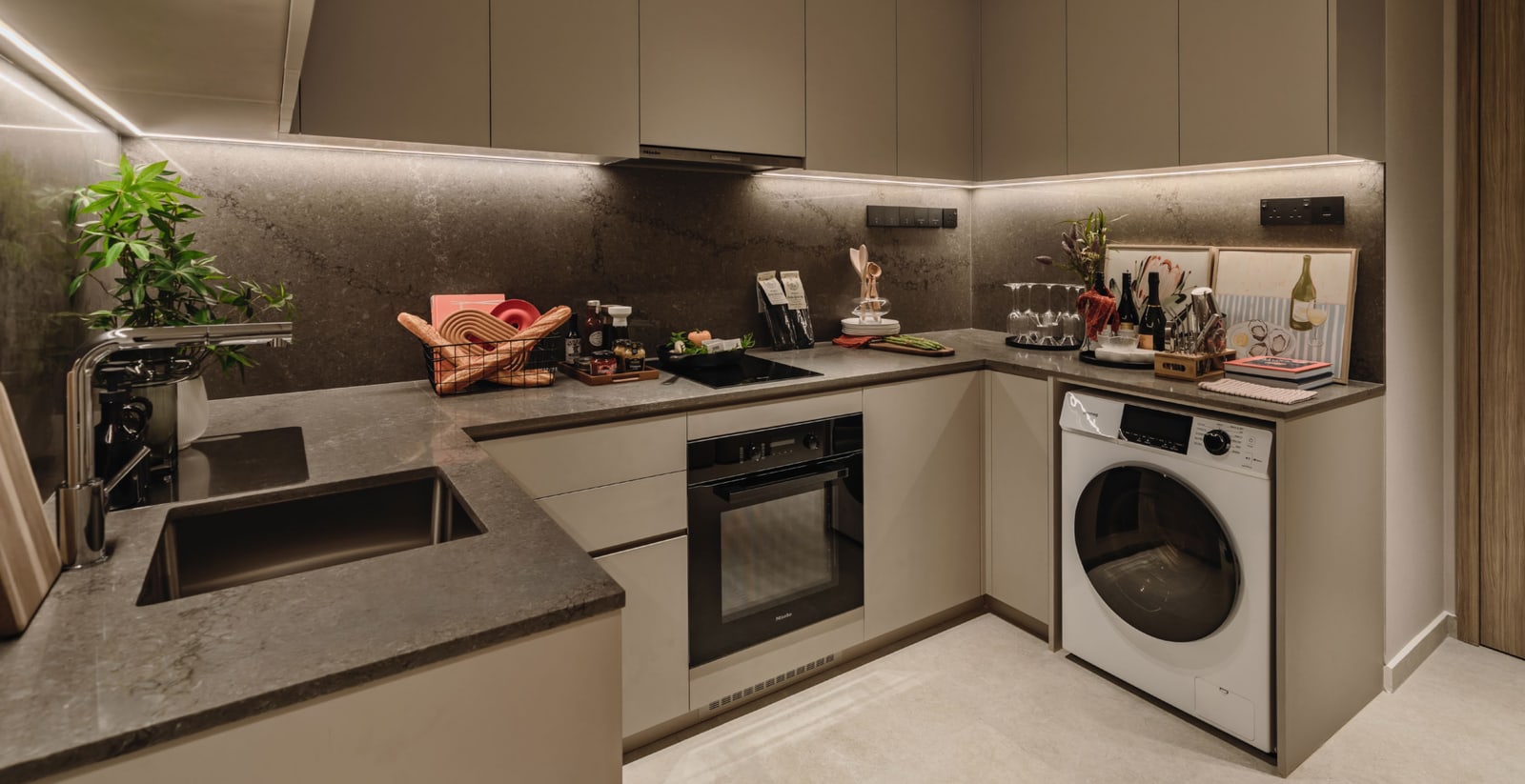 A kitchen with stone worktops, a built-in oven, a washing machine and branded fittings